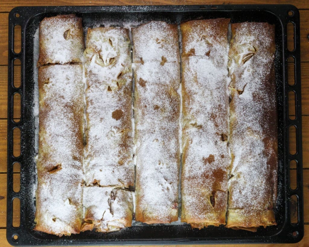 Dusting the plum strudel rolls with powderd sugar.